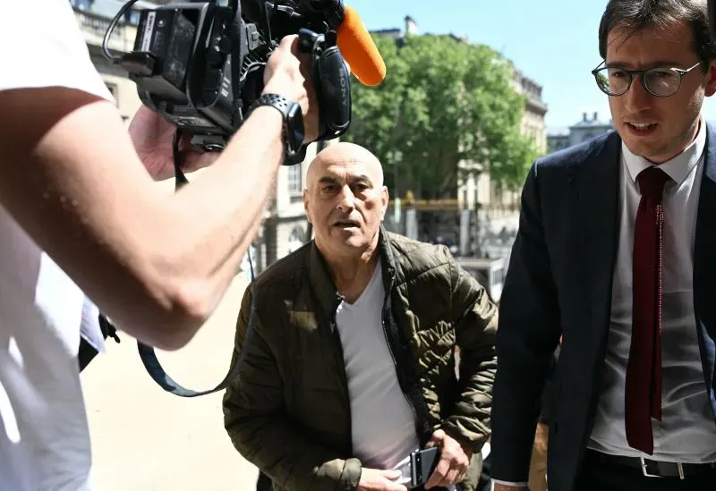 رجل مسن يخرج من المحكمة في باريس، محاطاً بالصحفيين، في سياق محاكمة متهمين بسرقة كيم كارداشيان في عام 2016.