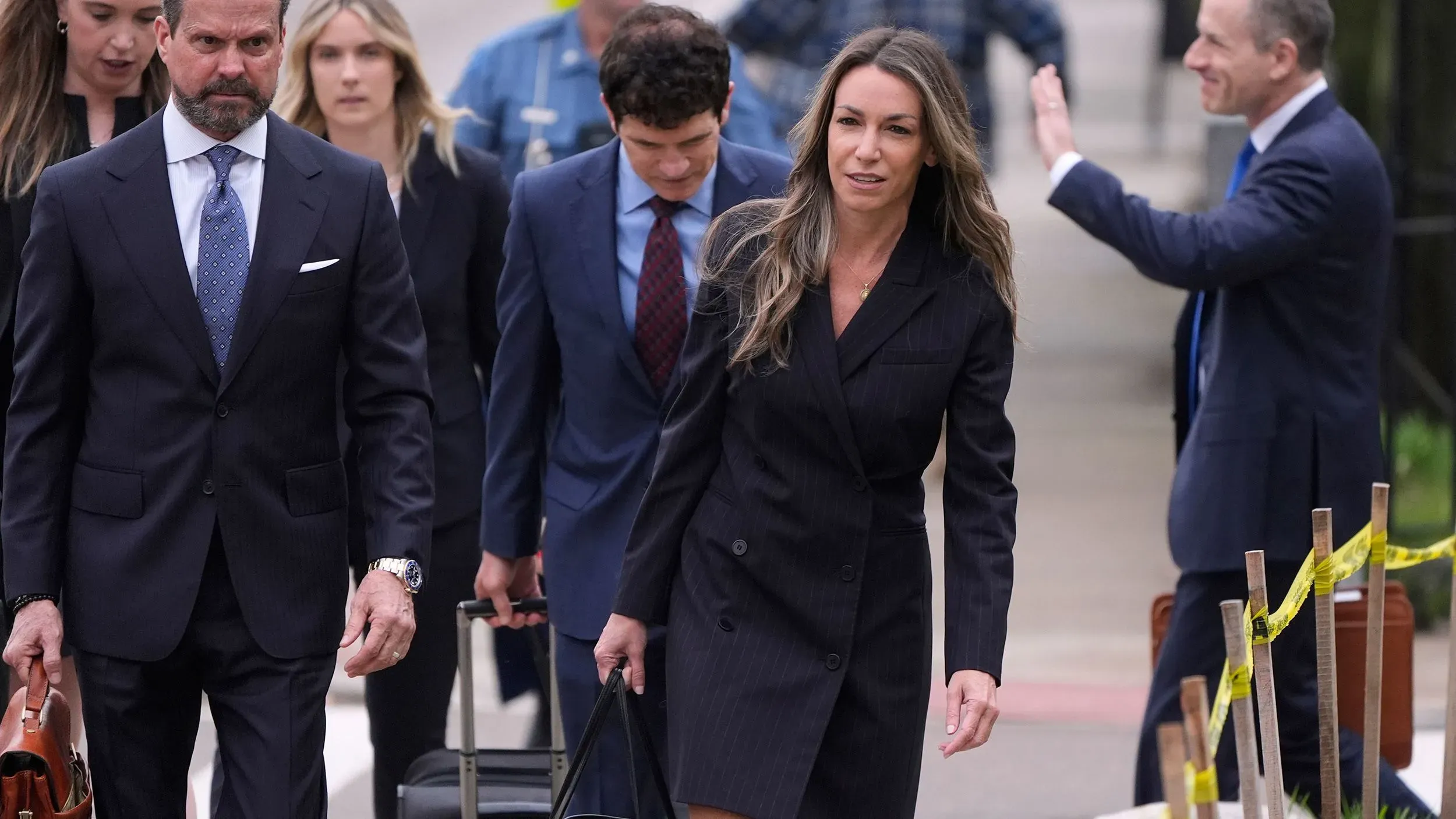 مجموعة من الأشخاص، بينهم كارين ريد، يغادرون المحكمة أثناء محاكمتها بتهمة القتل، مع وجود مؤيدين يحملون الأعلام الأمريكية في الخلفية.