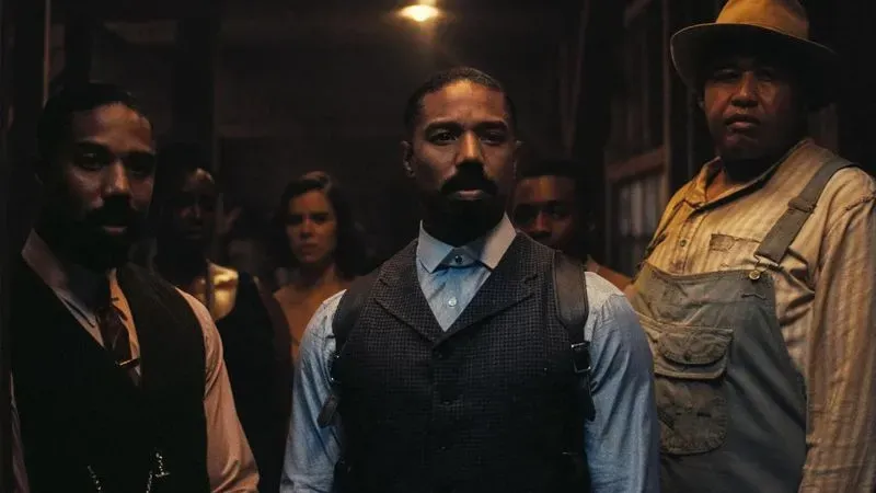 مجموعة من الشخصيات في مشهد درامي من فيلم "المذنبون"، حيث يظهر مايكل ب. جوردان مع مجموعة متنوعة من الشخصيات في خلفية مظلمة.