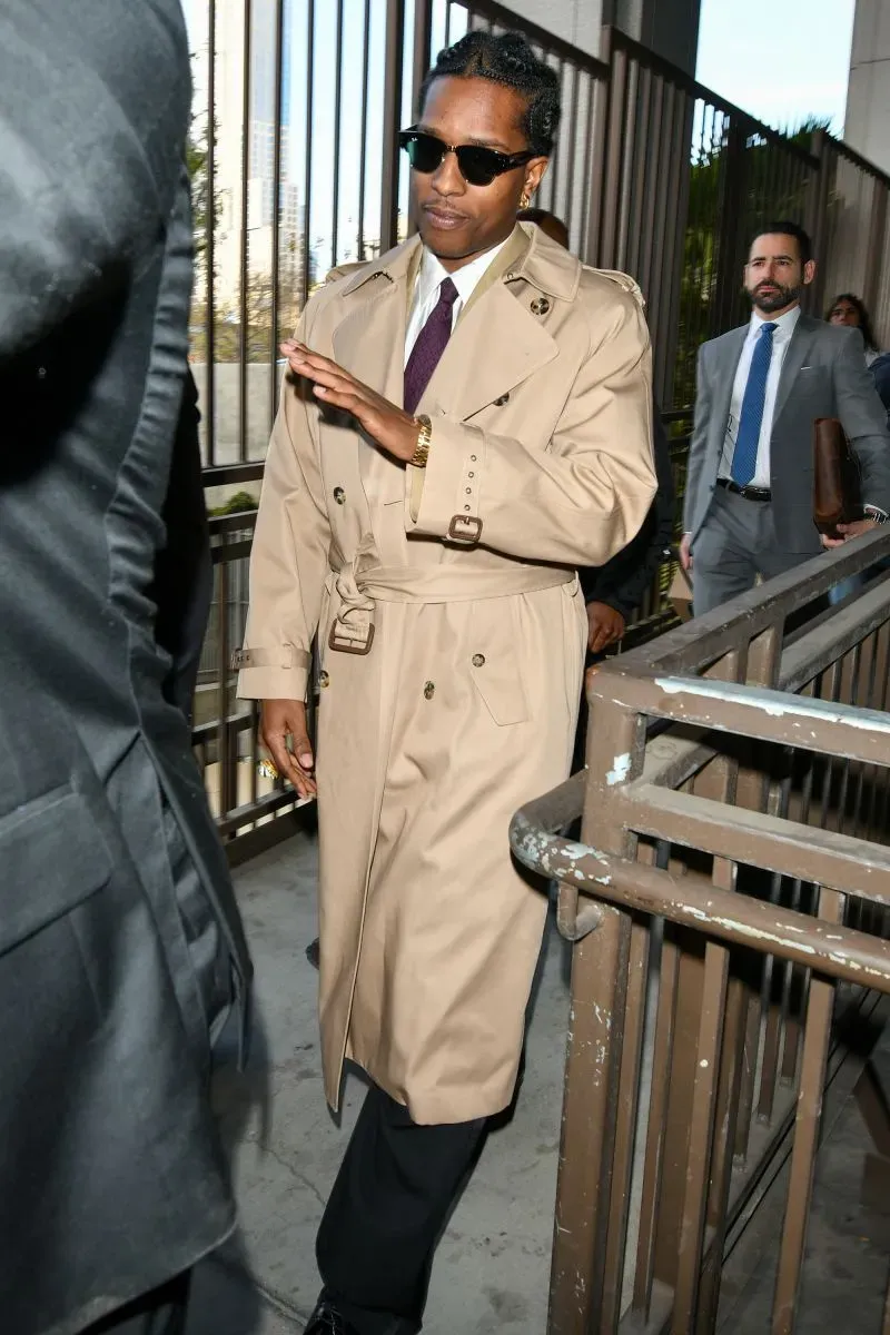 يظهر رجل يرتدي معطفًا بنيًا وقميصًا أبيض، مع نظارات شمسية، وهو يتجه نحو قاعة المحكمة في لوس أنجلوس.