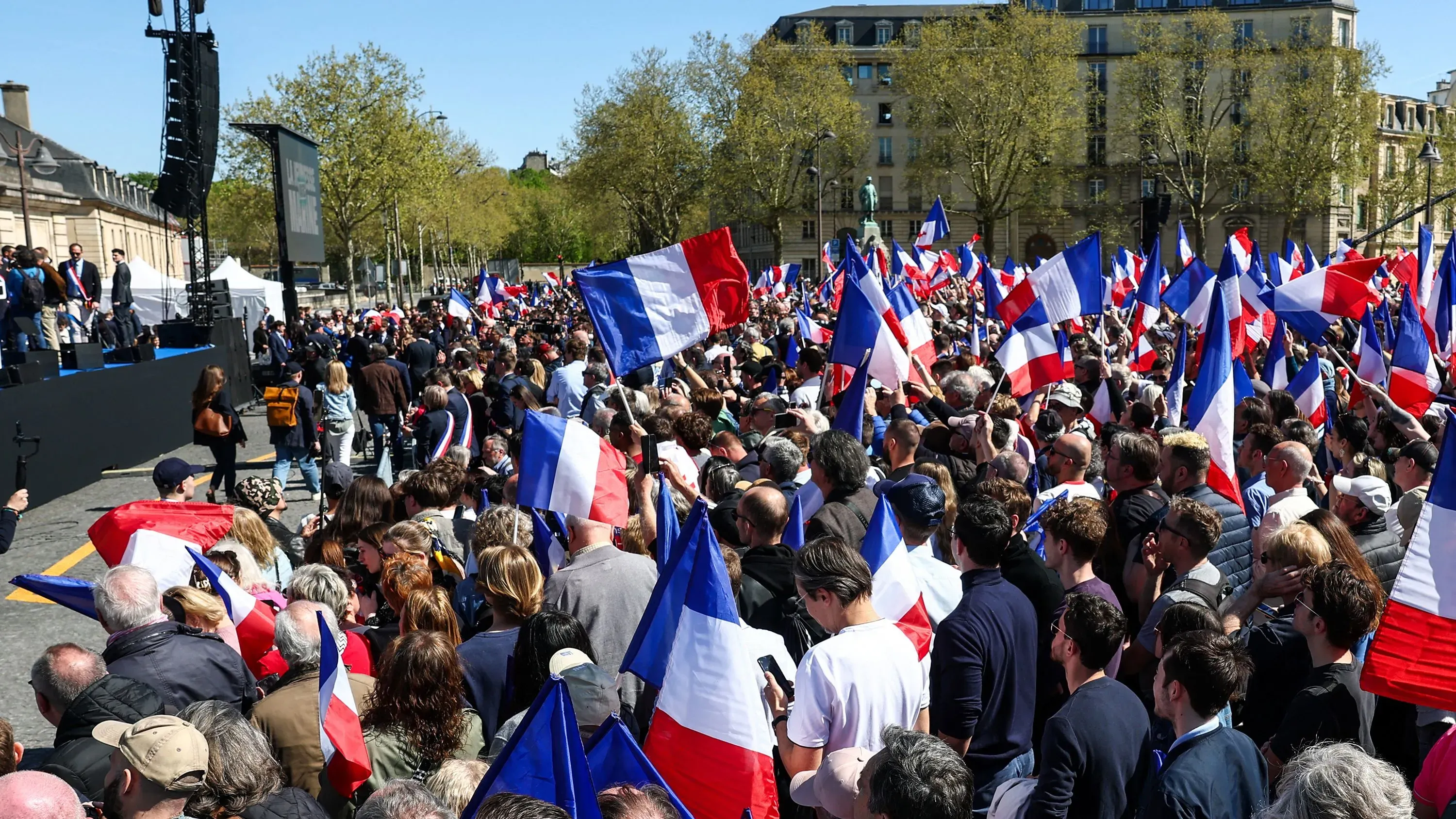 تجمع حشود من أنصار مارين لوبان في ساحة فوبان بباريس، حاملين الأعلام الفرنسية، احتجاجًا على حكم قضائي ضدها.