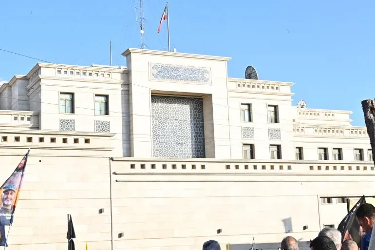 مبنى السفارة الإيرانية في لبنان، مع وجود أعلام وشخصيات تتظاهر أمامه، في سياق التوترات الدبلوماسية بين لبنان وإيران.