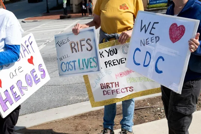 محتجون يحملون لافتات تعبر عن دعمهم لوكالة CDC، مع تحذيرات حول تأثير التخفيضات على الصحة العامة.
