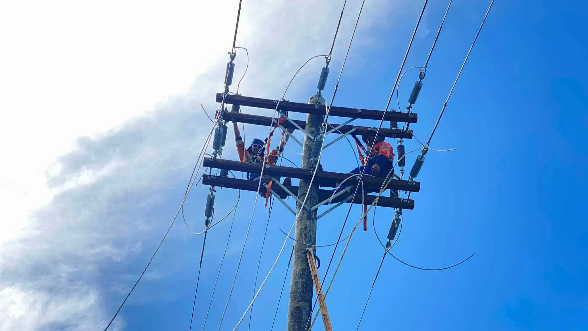 عمال يقومون بإصلاح خطوط الكهرباء على عمود في ساموا، في ظل أزمة انقطاع التيار الكهربائي المستمرة وتأثيرها على الحياة اليومية.