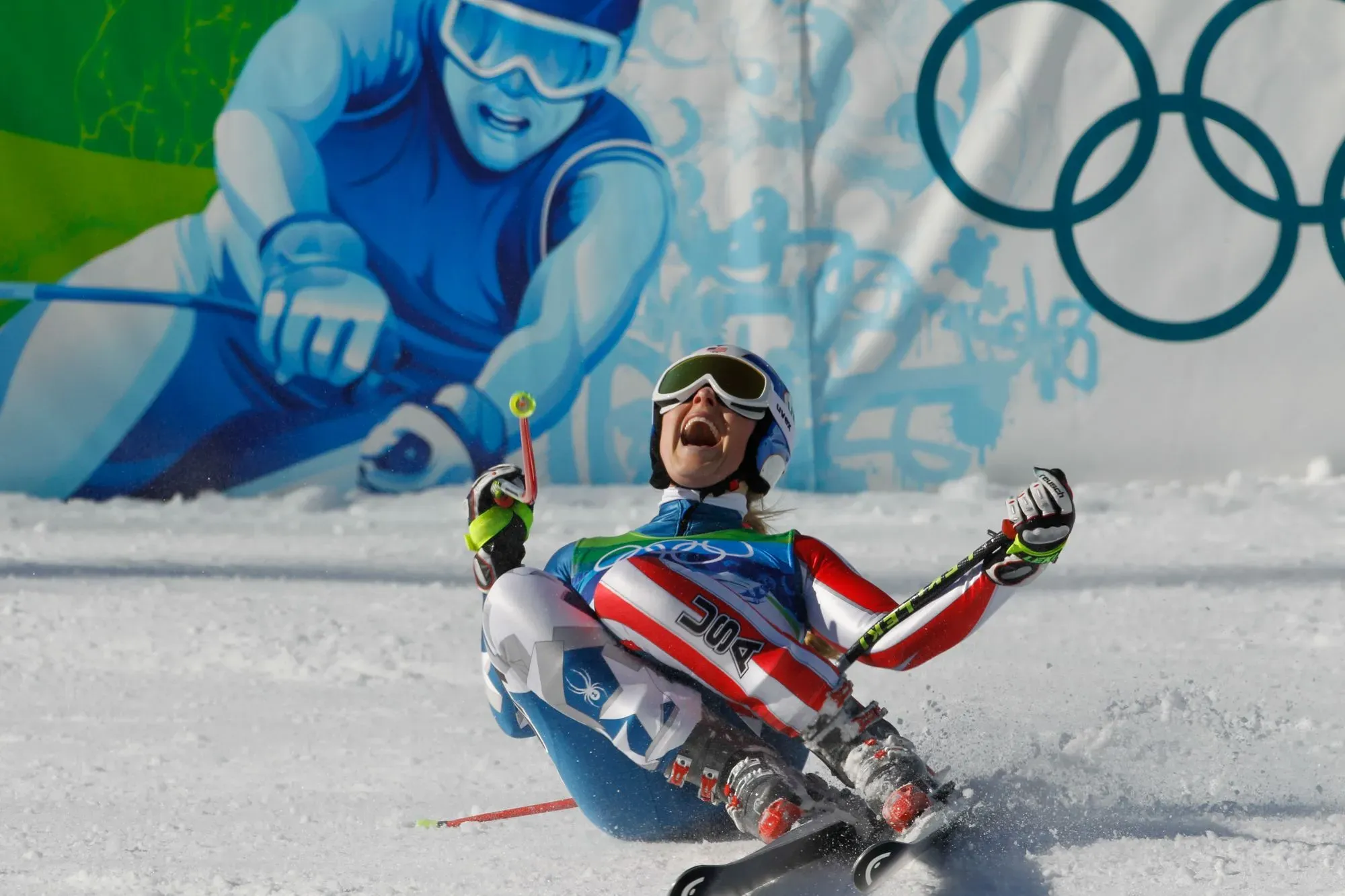 تظهر الصورة متزلجة تسقط على الثلج أثناء المنافسة، مع تعبير عن الألم على وجهها، وخلفها جدارية ملونة تمثل رياضة التزلج.