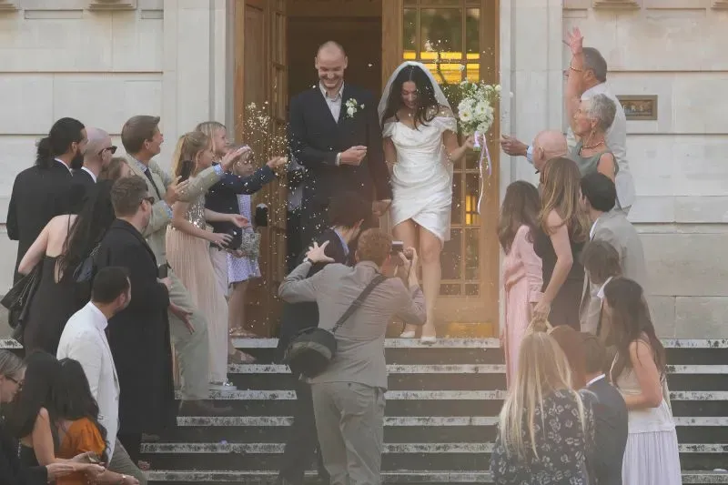 تشارلي إكس سي إكس تخرج من قاعة الزفاف بفستان قصير من فيفيان ويستوود، محاطة بالضيوف الذين يحتفلون برش الأرز.