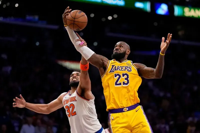 لاعب لوس أنجلوس ليكرز ليبرون جيمس يتجاوز مدافع نيويورك نيكس في مباراة مثيرة، حيث سجل 31 نقطة وساهم في الفوز 113-109.