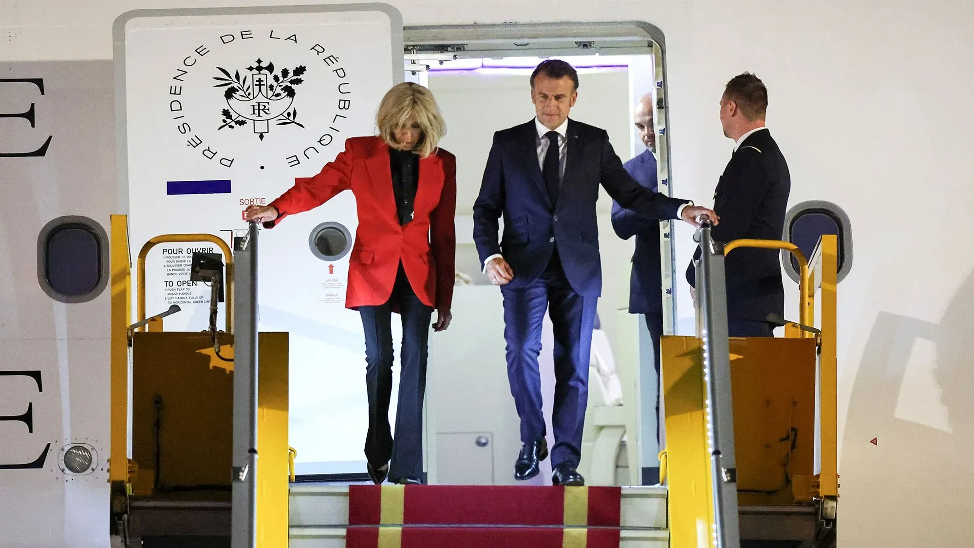 ماكرون وزوجته بريجيت ينزلان من الطائرة في فيتنام، حيث تبدو بريجيت وهي تدفع وجهه في لحظة غير متوقعة.