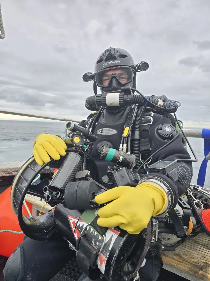 غواص يرتدي معدات الغوص الحديثة ويبتسم، مستعد لاستكشاف حطام السفينة SS Nantes الغارقة قبالة سواحل بريطانيا.