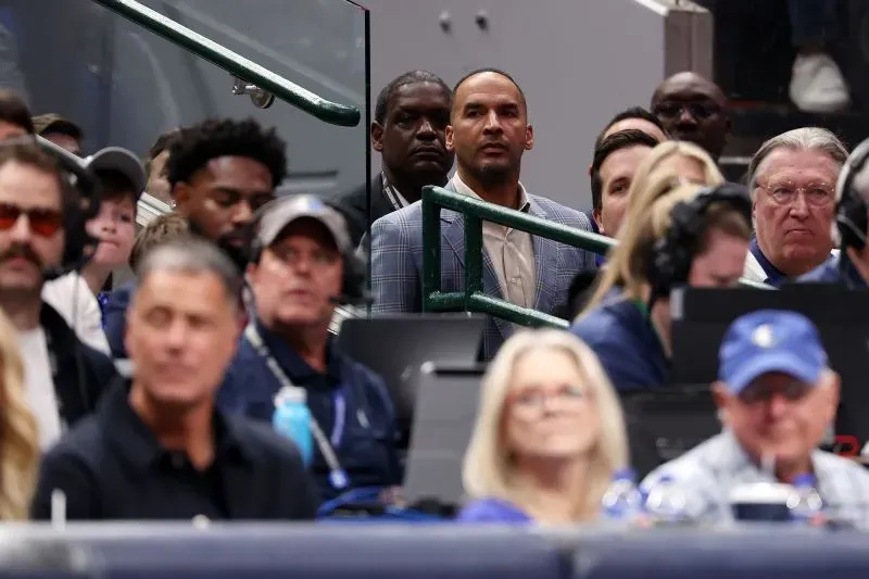 نيكو هاريسون، المدير العام لفريق دالاس مافريكس، يتابع مباراة في خلفية مشجعي الفريق، مع تعبيرات متوترة على وجهه بعد صفقة لوكا دونشيتش.