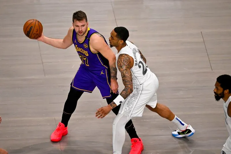 لوكا دونشيتش، لاعب لوس أنجلوس ليكرز، يت dribble الكرة بينما يتصدى له لاعب من فريق دالاس مافريكس، في مباراة مثيرة ضمن الدوري الأمريكي للمحترفين.