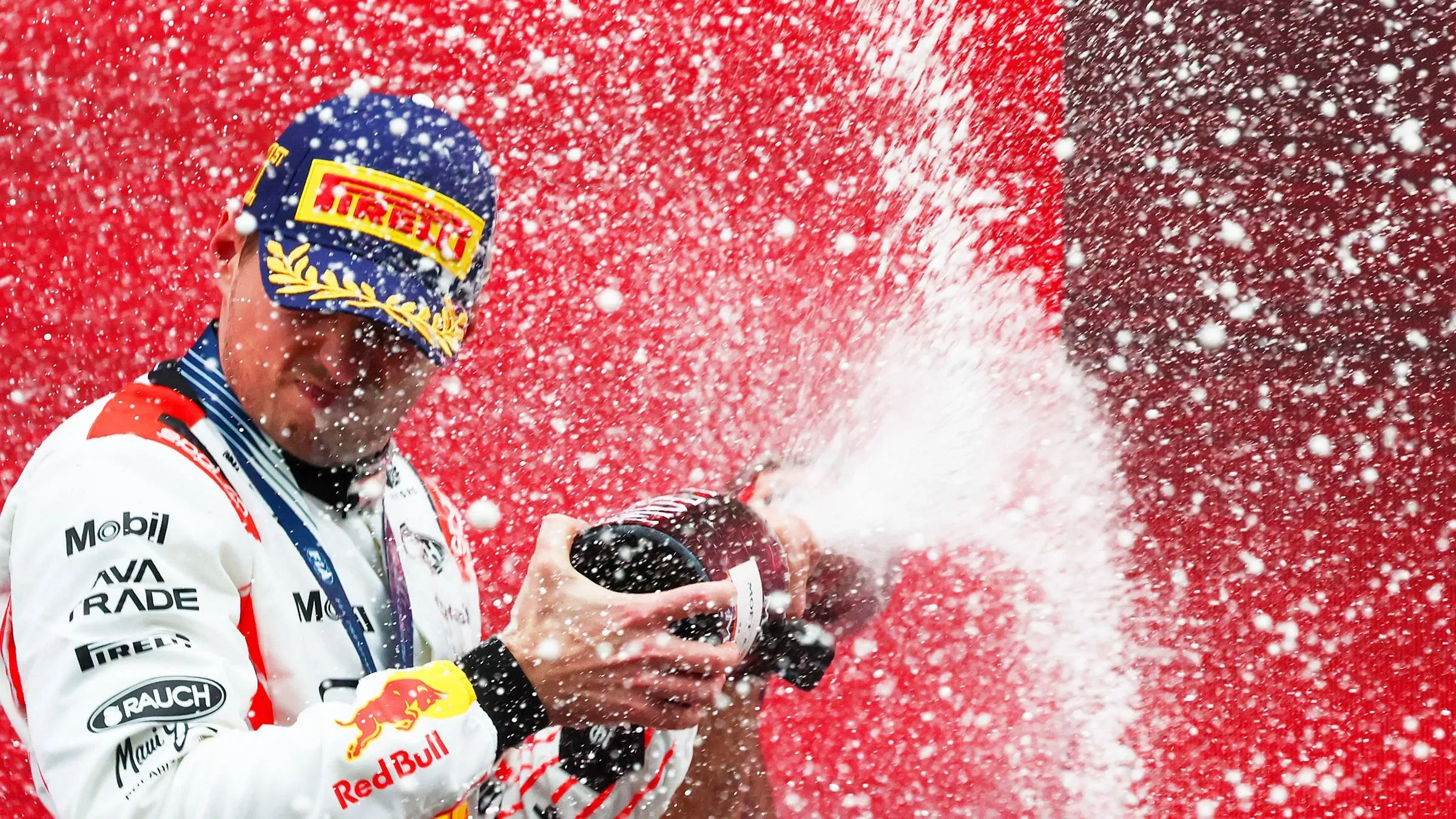 ماكس فيرستابن يحتفل بفوزه في جائزة اليابان الكبرى، وهو يرش الشمampagne في أجواء احتفالية مع خلفية حمراء، معبراً عن سعادته بالنجاح.