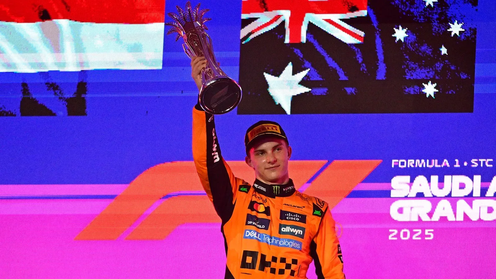 أوسكار بياستري يحتفل بفوزه في سباق جائزة السعودية الكبرى، رافعًا الكأس أمام خلفية علم أستراليا، بعد تنافس مثير مع ماكس فيرستابن.