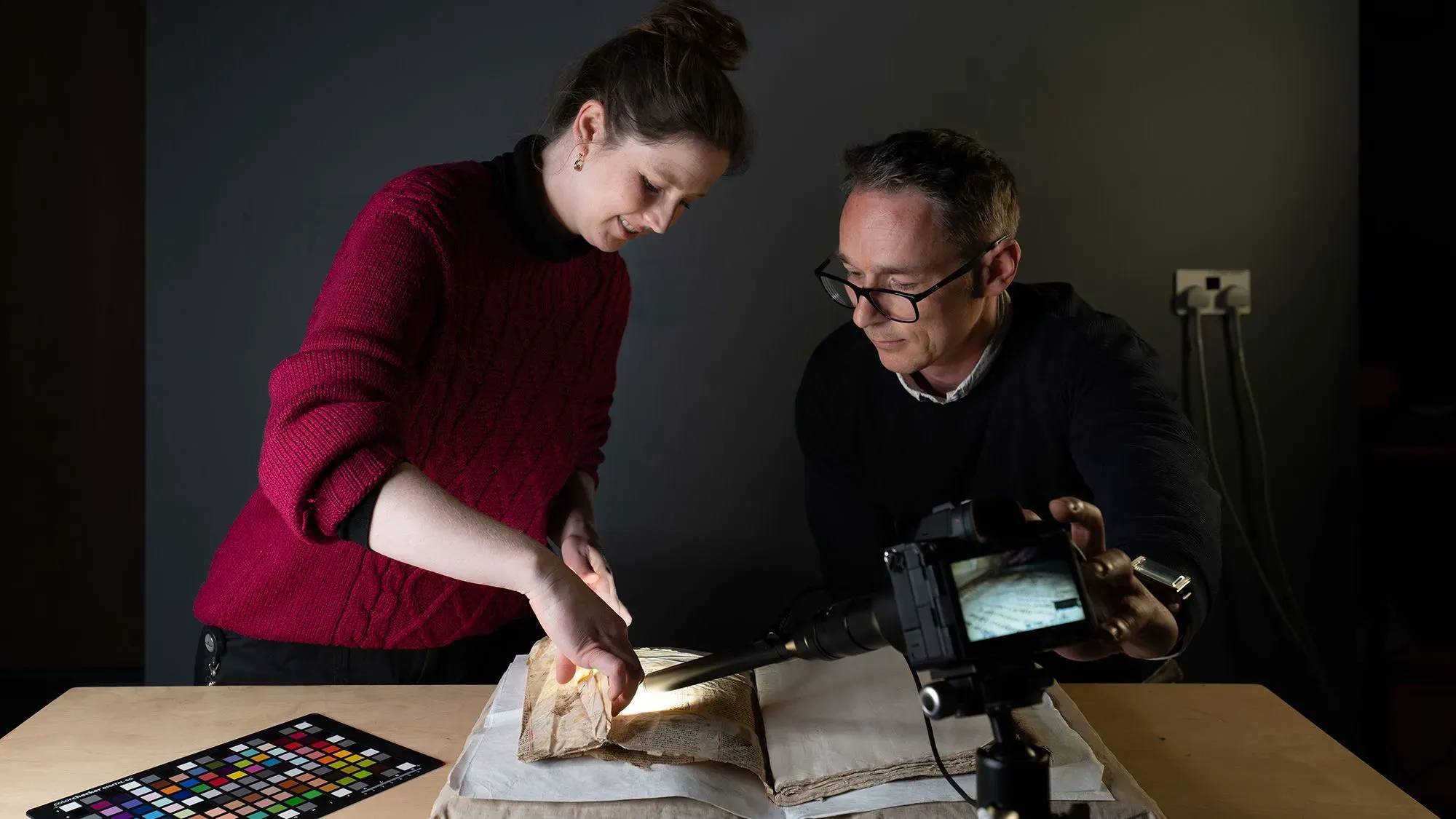 باحثون في مكتبة جامعة كامبريدج يقومون بفحص صفحات مخطوطة نادرة من القرن الثالث عشر تتعلق بقصص ميرلين والملك آرثر.