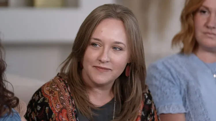 تظهر كاتي، امرأة ذات شعر بني طويل، تتحدث بجدية عن تجربتها مع القومية المسيحية والأصولية، محاطة بأخريات في جلسة نقاش.