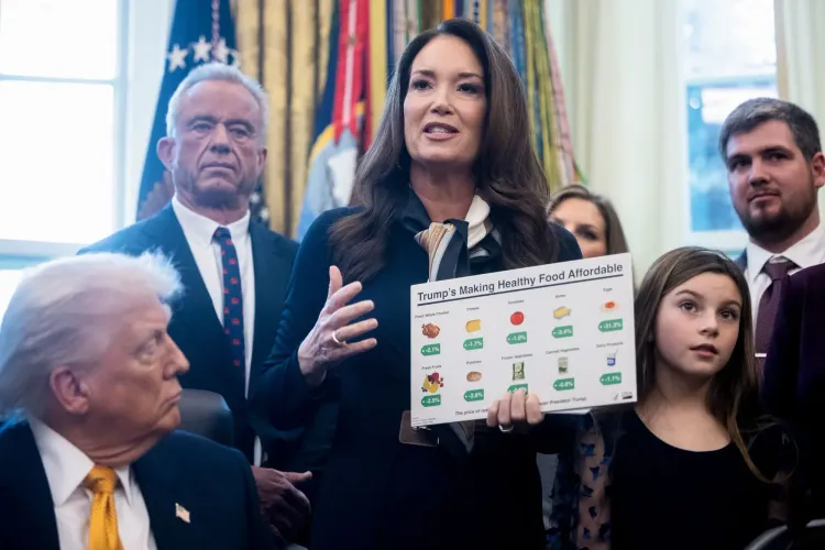 امرأة تتحدث في مؤتمر صحفي، تحمل لافتة توضح كيفية جعل الطعام الصحي في متناول الجميع، مع ترامب ومساعدين خلفها.