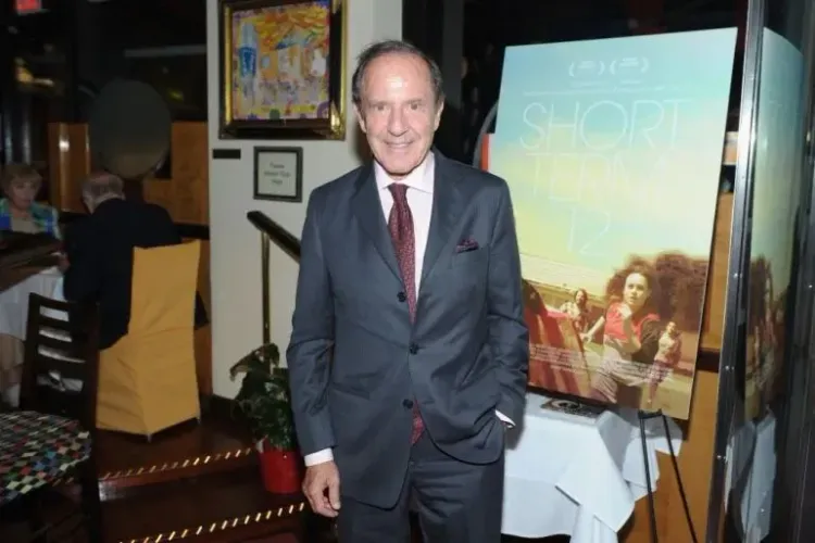 مورتيمر زوكرمان، قطب الإعلام والعقارات، يقف مبتسمًا في حدث، مع خلفية تشير إلى مشروعاته الإعلامية.