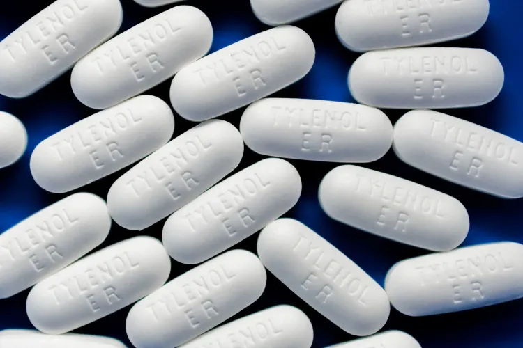 أقراص تايلينول البيضاء مرصوصة بشكل عشوائي على خلفية زرقاء، مما يعكس الجدل حول تأثيراتها على النساء الحوامل.