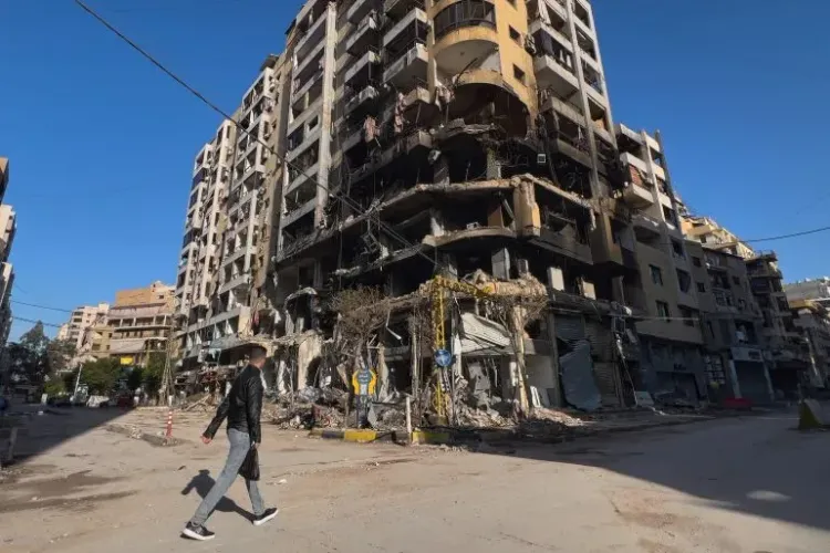 مبنى سكني مدمر في بشامون، بيروت، يظهر آثار الغارة الإسرائيلية، مع وجود حطام في الشارع وشخص يمشي بجوار المبنى.