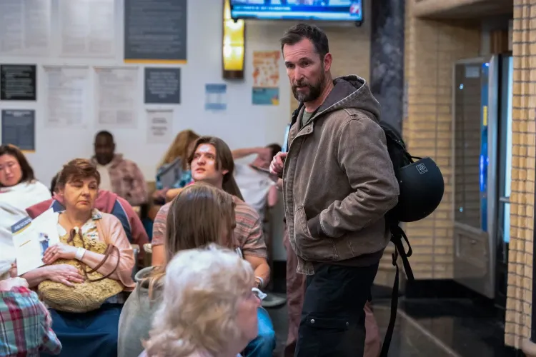 مشهد من المسلسل "ذا بيت" يظهر الدكتور روبي وسط مرضى ينتظرون في قسم الطوارئ، مع التركيز على التوترات في بيئة العمل.