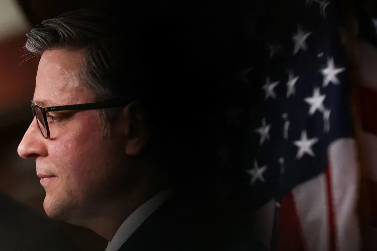 مايك جونسون، رئيس مجلس النواب الأمريكي، يظهر في صورة جانبية مع العلم الأمريكي خلفه، مع التركيز على تعبير وجهه الجاد.