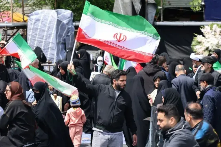 محتجون إيرانيون يحملون الأعلام الوطنية في تجمع حاشد، مع التركيز على الأجواء السياسية المتوترة في المنطقة.