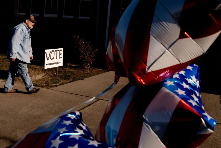 رجل يسير نحو لافتة "صوت" بينما تتدلى بالونات مزينة بالعلم الأمريكي، مما يعكس أجواء الانتخابات.
