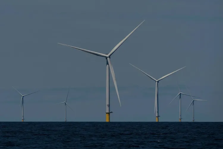 تظهر الصورة مجموعة من توربينات الرياح البحرية في المحيط، مما يعكس جهود الولايات المتحدة في استخدام الطاقة المتجددة لمواجهة ارتفاع أسعار الكهرباء.