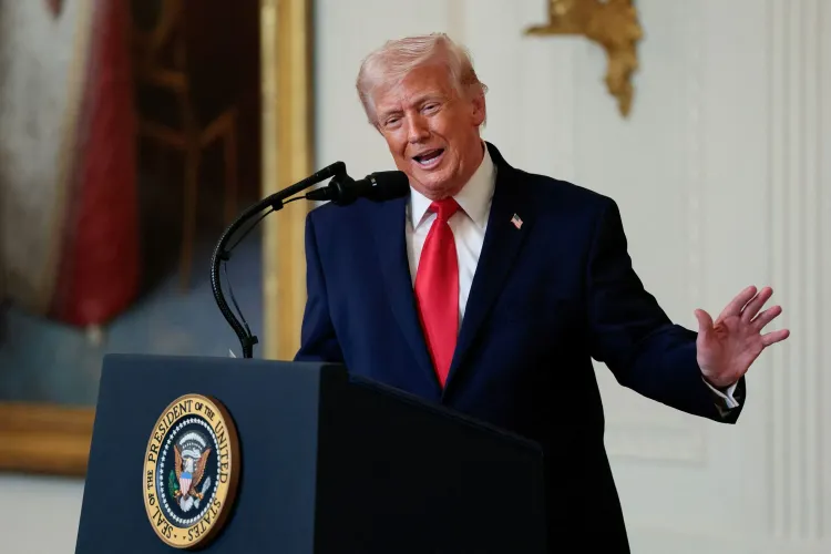 تظهر الصورة الرئيس الأمريكي السابق دونالد ترامب وهو يتحدث أمام ميكروفون، مرتديًا بدلة زرقاء وقميصًا أبيض مع ربطة عنق حمراء، في سياق مناقشة السياسة الأمريكية.