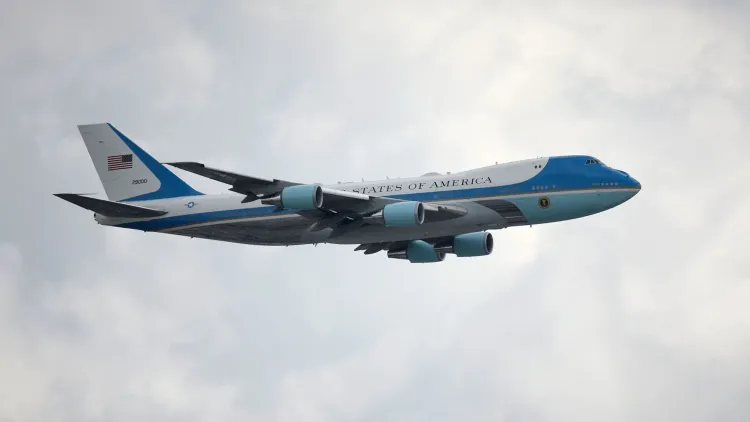 طائرة بوينج 747-800 للرئاسة الأمريكية في السماء، تحمل تصميمًا باللونين الأزرق والأبيض مع علم الولايات المتحدة على الذيل.