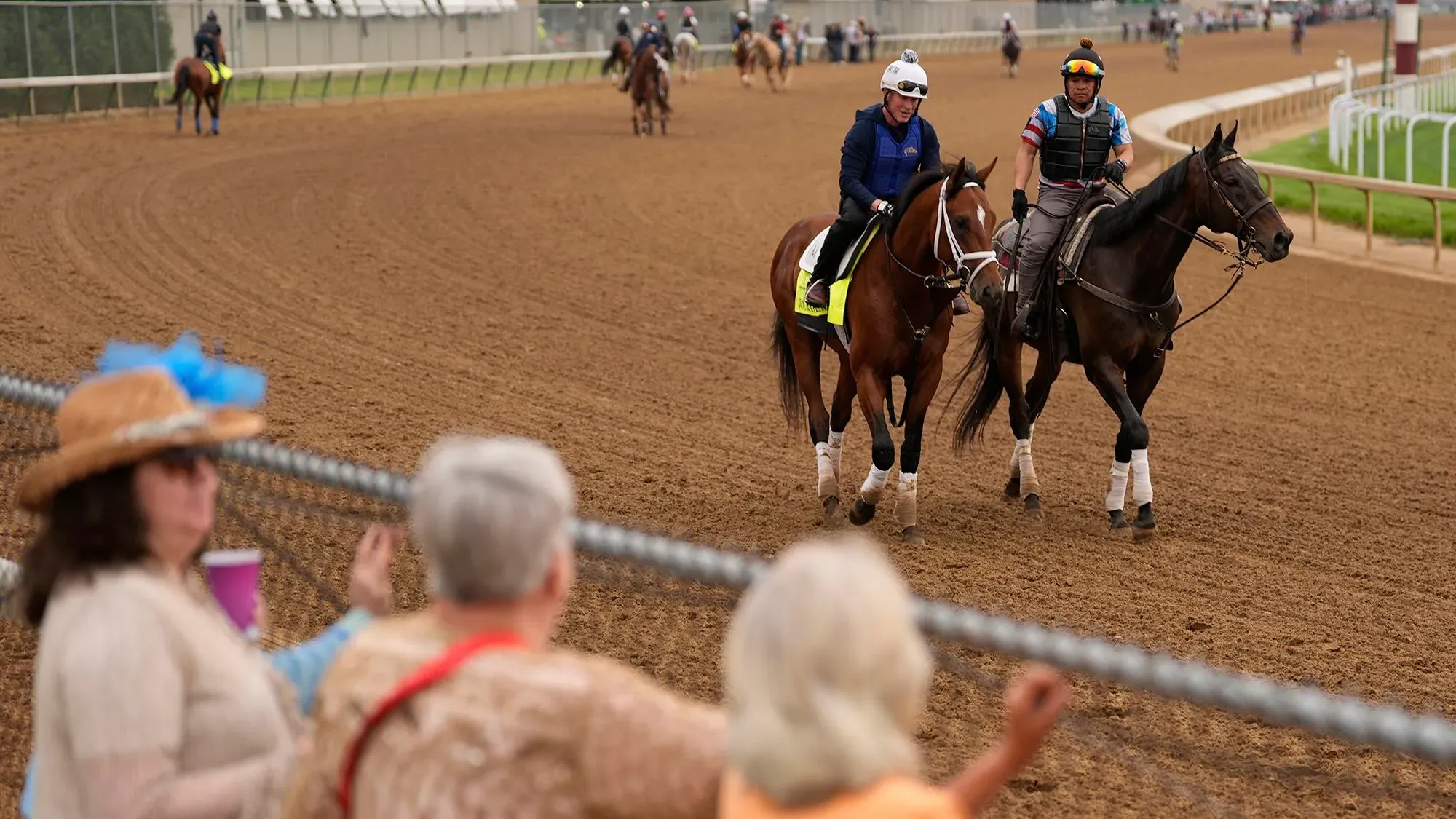 مشهد من مضمار سباق كنتاكي ديربي حيث يتدرب الخيول، مع حضور جماهيري يتفاعل مع الحدث.