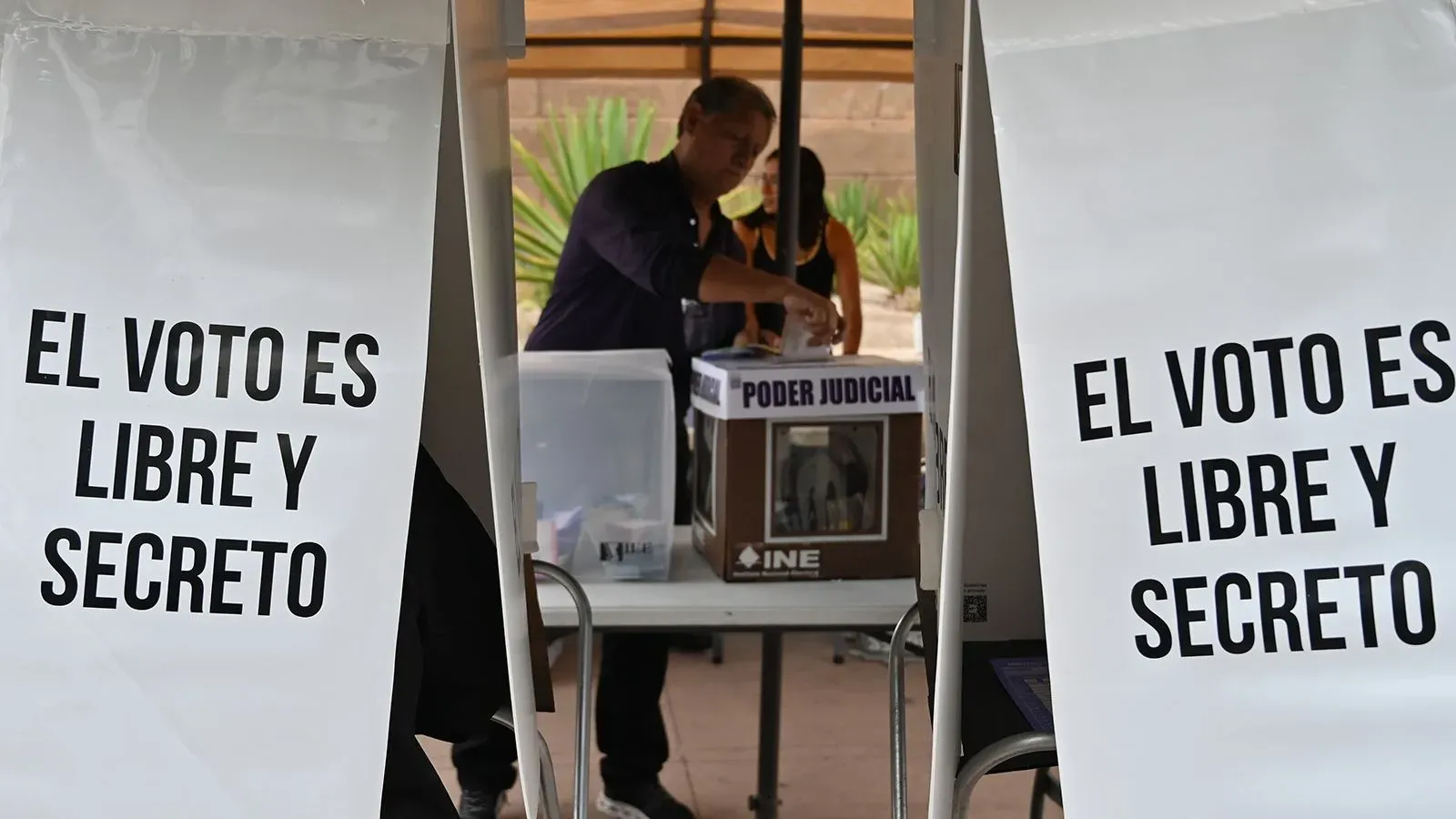 مركز اقتراع في المكسيك يظهر لافتات تشير إلى أن التصويت حر وسري، مع شخص يقوم بإدخال صوته في صندوق الاقتراع.