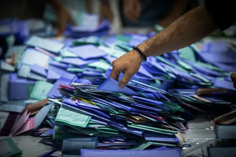 يد تظهر وهي تفحص أوراق الاقتراع الملونة المكدسة بعد الانتخابات القضائية في المكسيك، حيث سجلت نسبة مشاركة منخفضة.