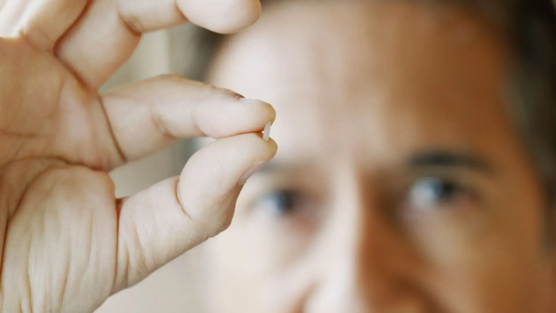 رجل يحمل جسيمًا بلاستيكيًا دقيقًا بين أصابعه، مما يبرز المخاطر المرتبطة بانتشار الجراثيم الخارقة المقاومة للمضادات الحيوية.