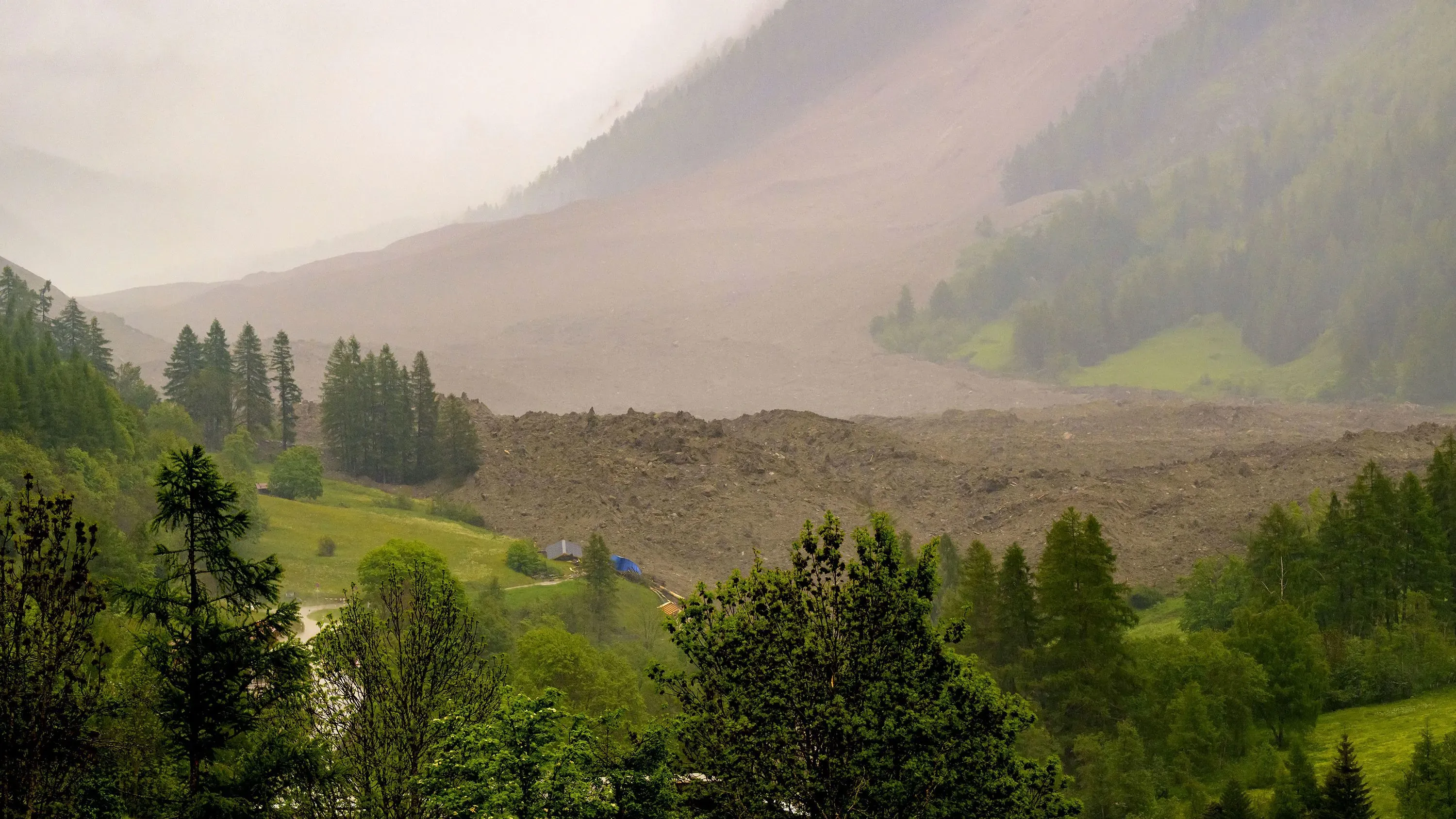 انهيار جليدي ضخم يغطي جزءًا من قرية بلاتن السويسرية، مع وجود أنقاض المباني والأشجار المحيطة في الوادي.