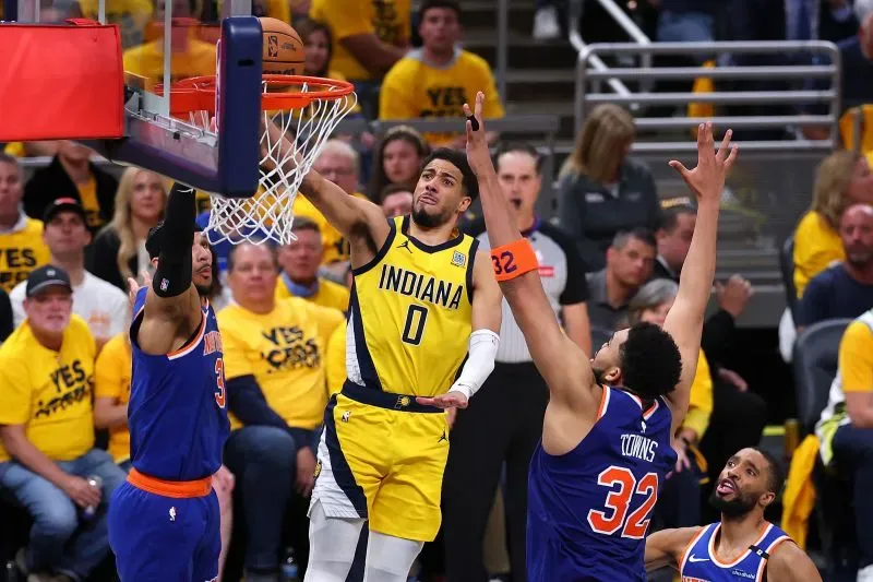 لاعب إنديانا يسجل نقطة في السلة خلال مباراة حماسية، مع تواجد لاعبي الفريق المنافس في الخلفية وجمهور متحمس.