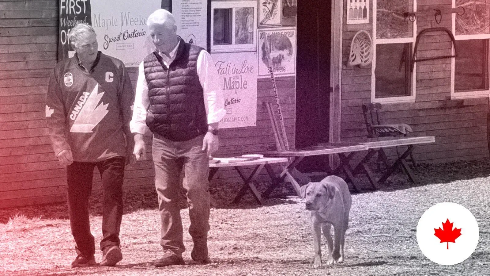 رجلان يسيران في منطقة ريفية بكندا، يرتدي أحدهما سترة تحمل شعار كندا، بينما يرافقهما كلب. تظهر خلفية من لافتات ومشاهد طبيعية.