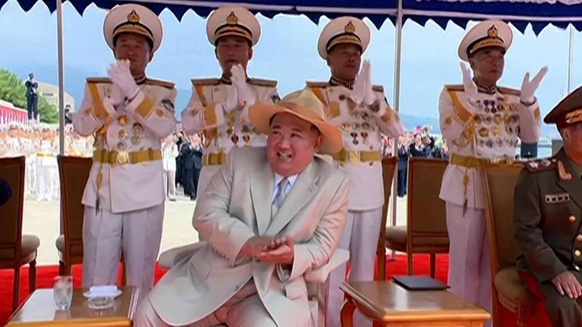 كيم جونغ أون يجلس مبتسمًا وسط مجموعة من الضباط العسكريين، خلال احتفال رسمي يتعلق بإعادة تعويم مدمرة كورية شمالية.