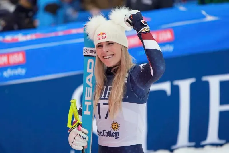 ليندسي فون تحتفل بفوزها في سباق التزلج، مرتدية زيها الرياضي وقبعة بيضاء، مع خلفية تحمل شعار ريد بول.