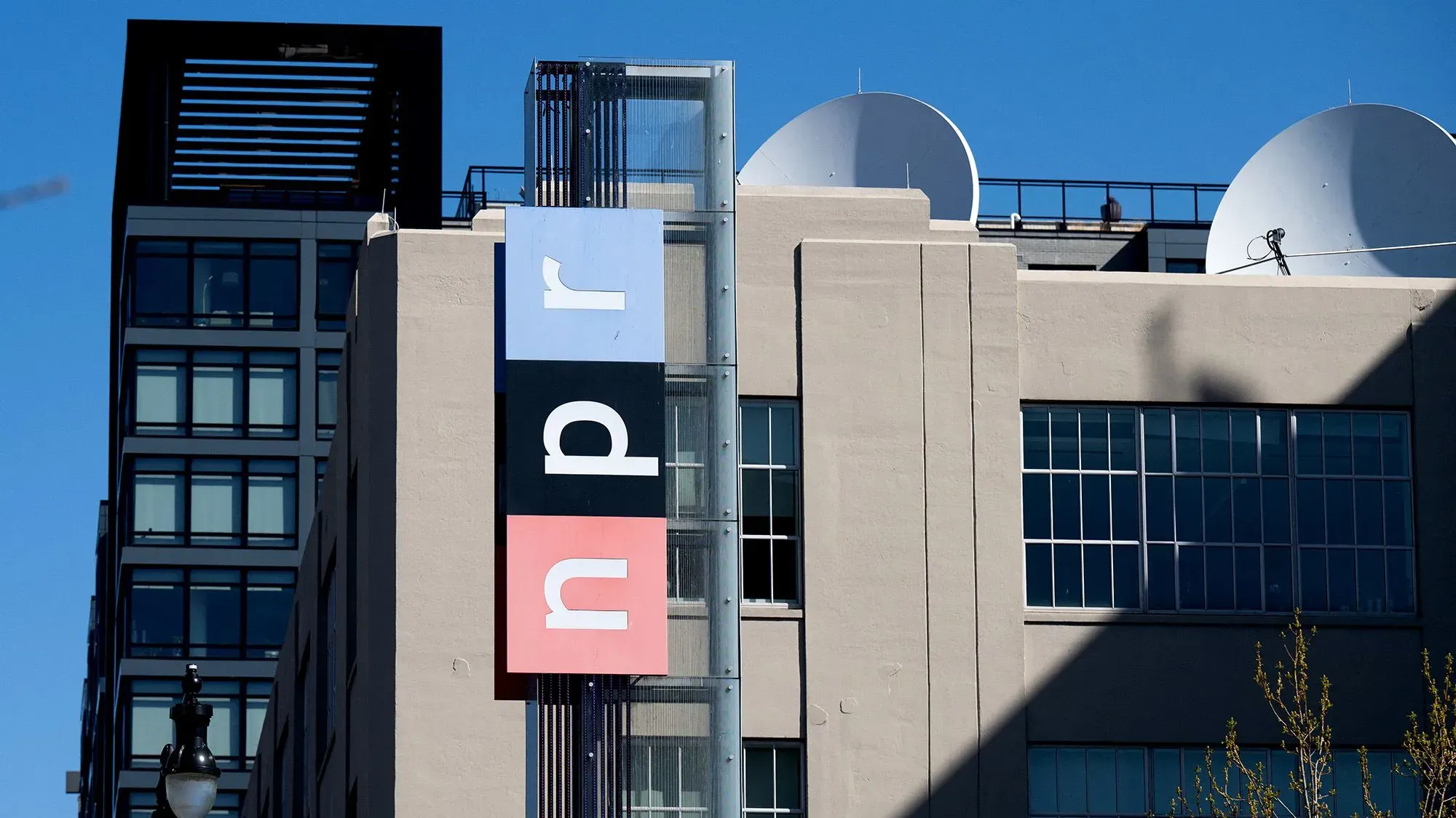 مبنى الإذاعة الوطنية العامة (NPR) في واشنطن، مع لافتة تحمل شعار NPR، يبرز أهمية الإعلام العام في مواجهة التهديدات السياسية.
