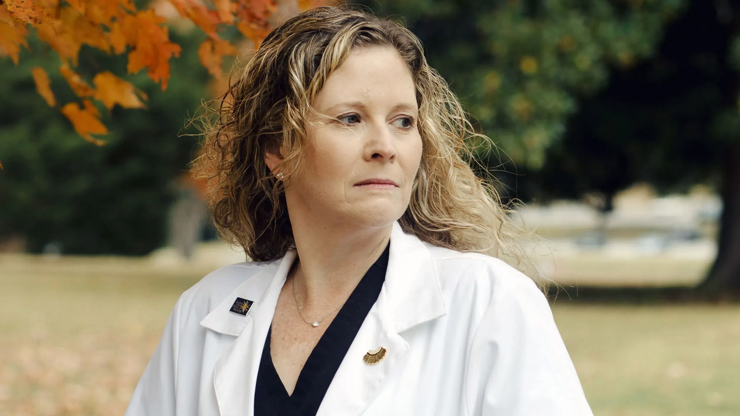 طبيبة نساء وتوليد تتأمل في حديقة، تعكس التحديات القانونية والأخلاقية التي تواجهها في ظل قيود الإجهاض في الولايات المتحدة.