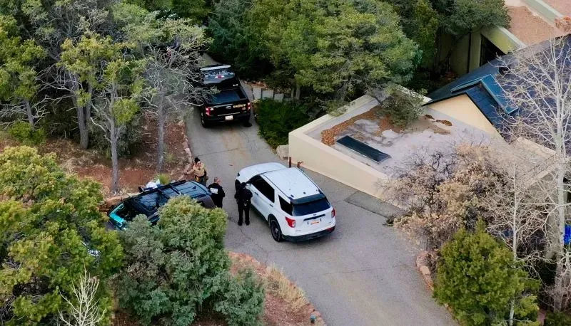 موقع الحادث خارج منزل الممثل جين هاكمان في سانتا في، حيث تتواجد سيارات الشرطة وسط أشجار كثيفة، بعد العثور على الزوجين متوفيين.