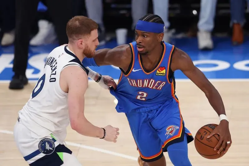 لاعب فريق أوكلاهوما سيتي ثاندر يت dribble الكرة بينما يواجه مدافعاً من مينيسوتا تمبروولفز في مباراة حاسمة ضمن نهائيات المؤتمر الغربي.
