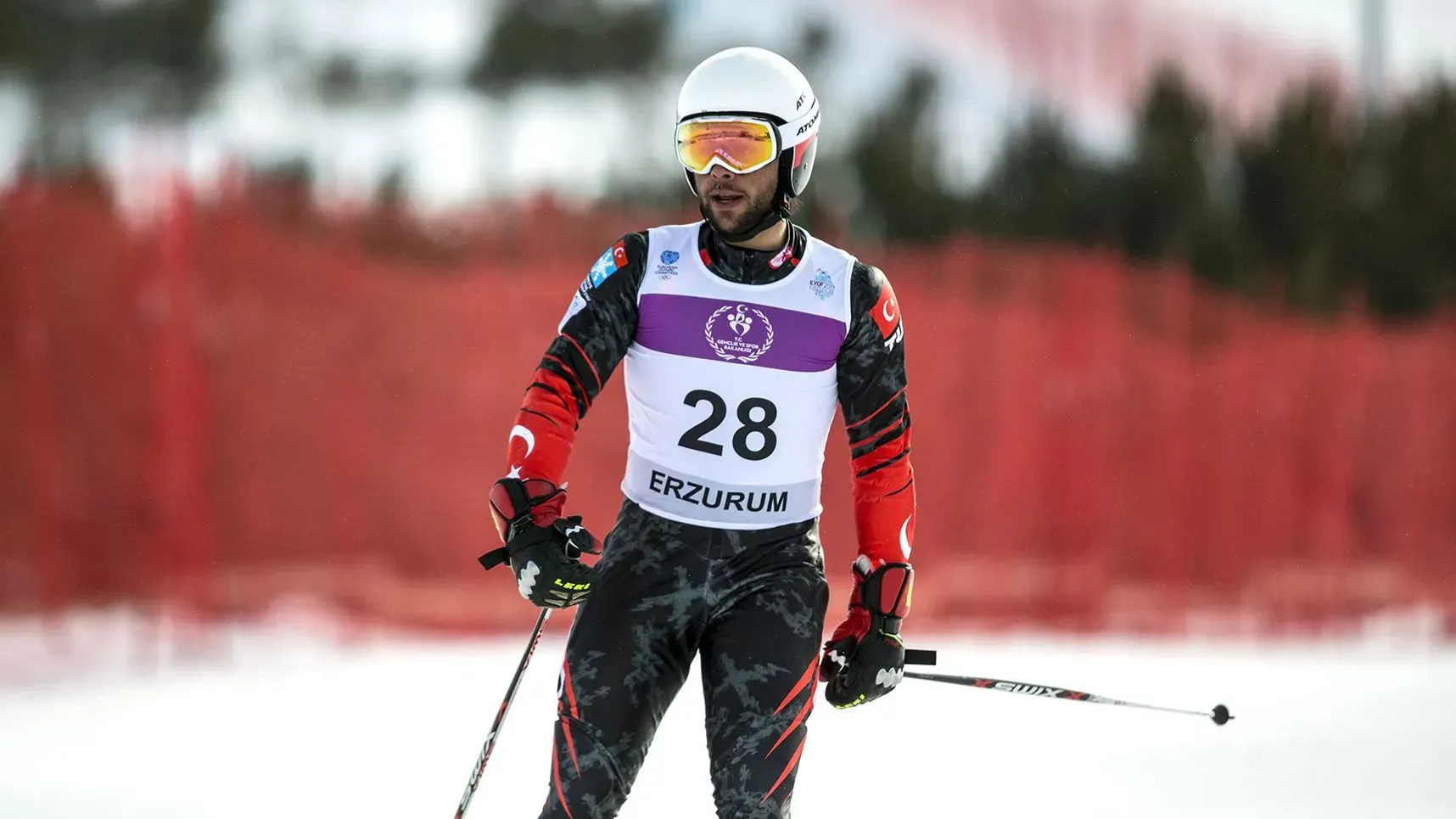 تظهر الصورة المتزلج الأولمبي بيركين أوستا خلال المنافسة في بطولة التزلج، حيث يرتدي زي فريقه ويستعد للانطلاق في مسار التزلج.