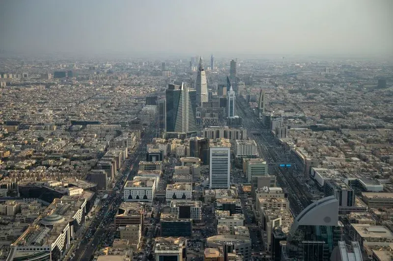 منظر شامل لمدينة الرياض، يظهر ناطحات السحاب والمباني الحديثة، مع التركيز على التطورات في البنية التحتية للسيارات الكهربائية.