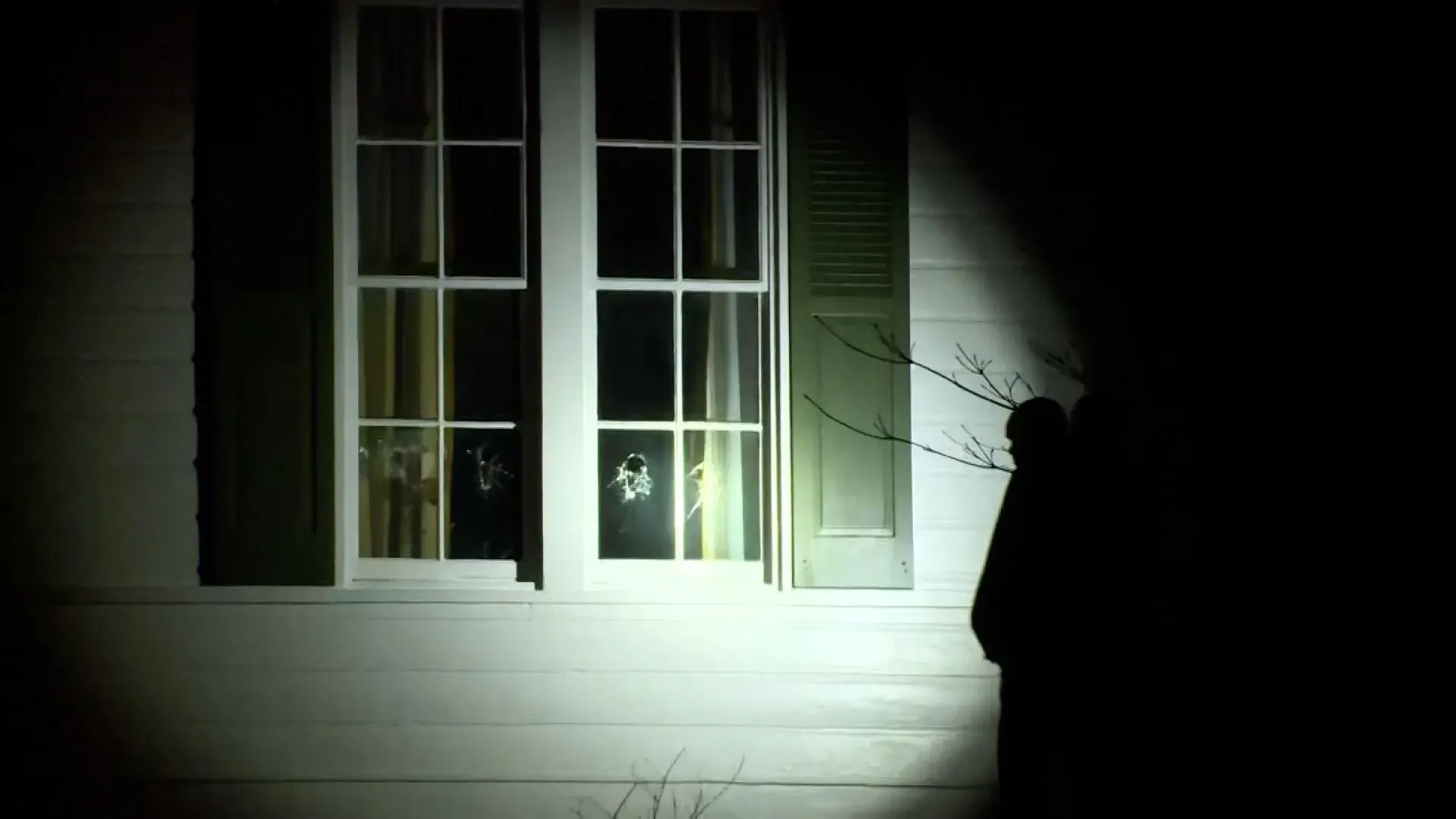 أضرار واضحة في نوافذ منزل نائب الرئيس جيه دي فانس، مع وجود شخص بالقرب من المنزل في ظروف مظلمة، بعد حادث اقتحام محتمل.