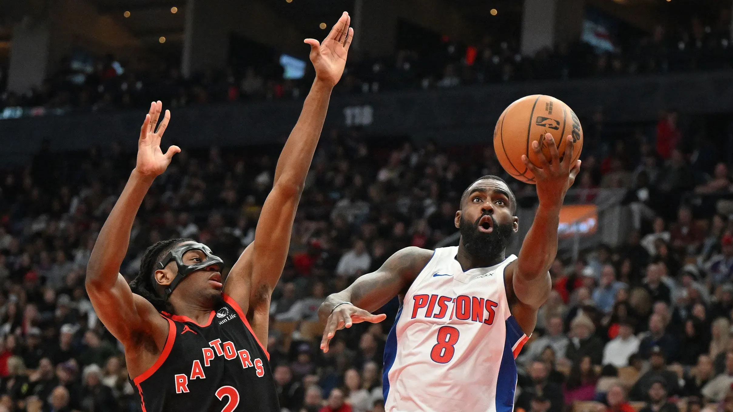 لاعب من ديترويت بيستونز يسجل نقطة أثناء مواجهة مع لاعب من تورونتو رابتورز، في مباراة حاسمة ضمن الدوري الأمريكي للمحترفين.