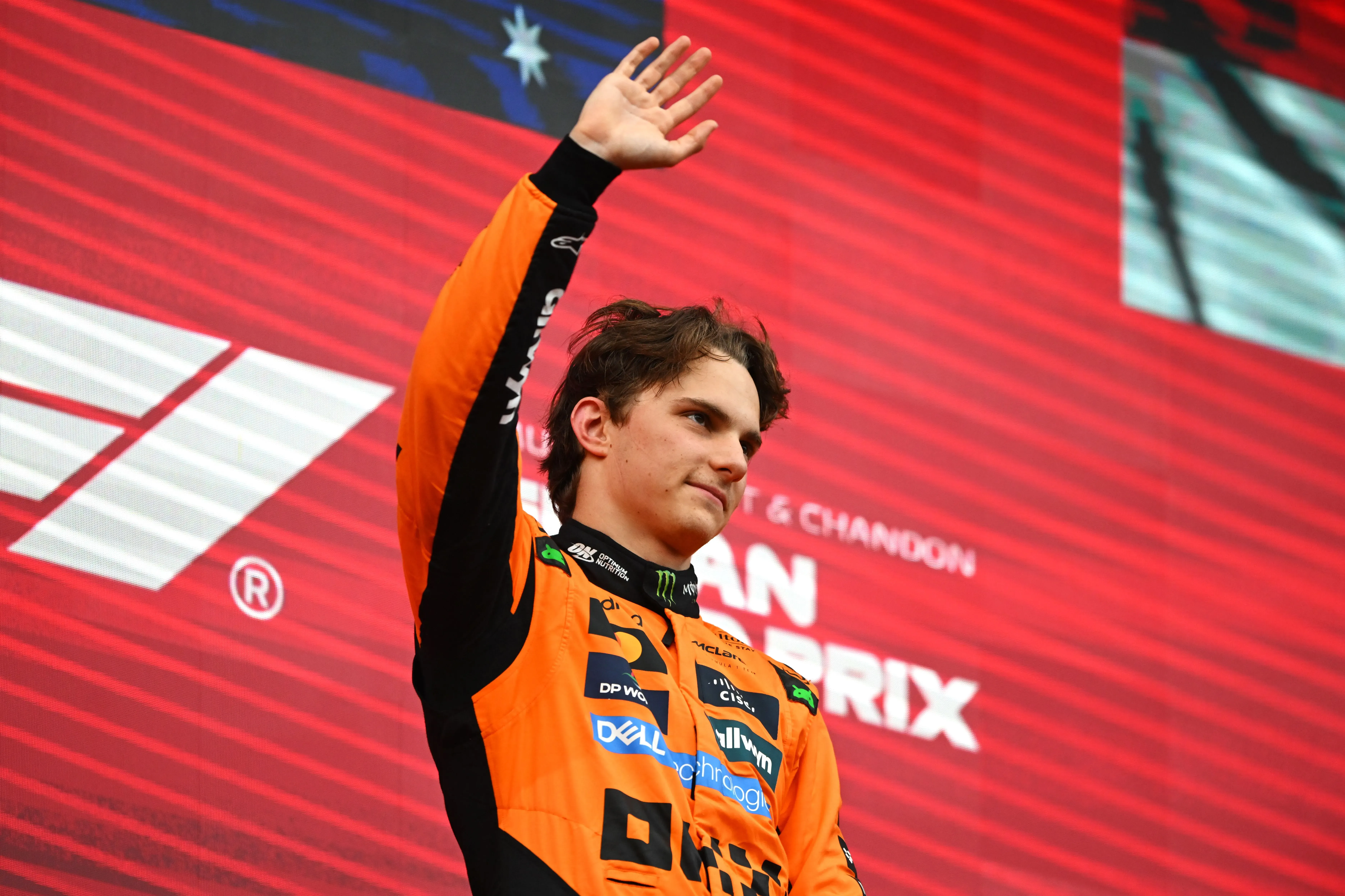 بياستري يحيي الجماهير بعد فوزه في سباق الجائزة الكبرى البلجيكي، مع خلفية تحمل شعار الفورمولا واحد.