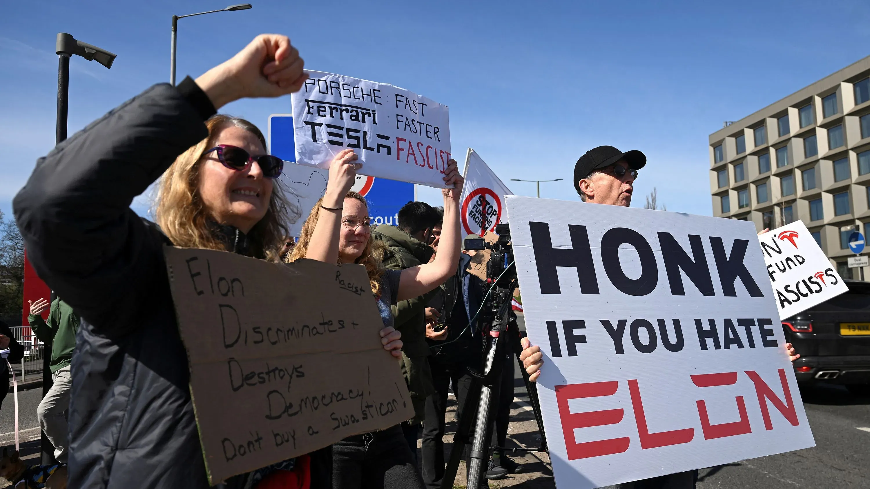 محتجون يتظاهرون ضد إيلون ماسك أمام منشأة تسلا، رافعين لافتات تدعو إلى مقاطعة الشركة بسبب سياساته المثيرة للجدل.