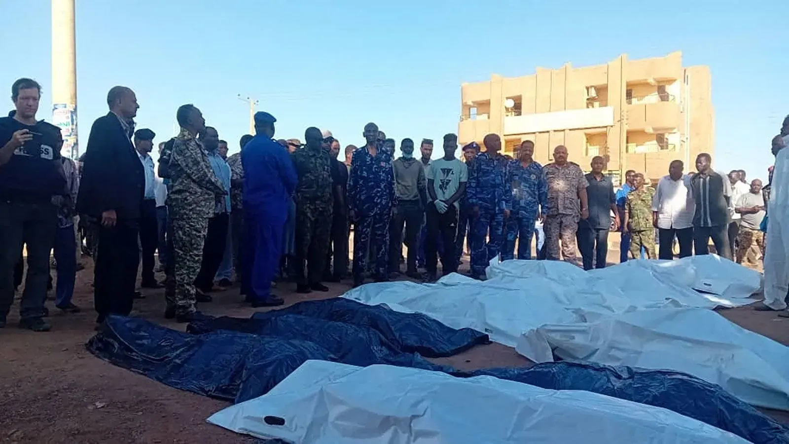 حشود من الناس تتجمع حول جثث مغطاة في سوق صابرين بأم درمان بعد هجوم قوات الدعم السريع، مما يعكس آثار الحرب الأهلية في السودان.